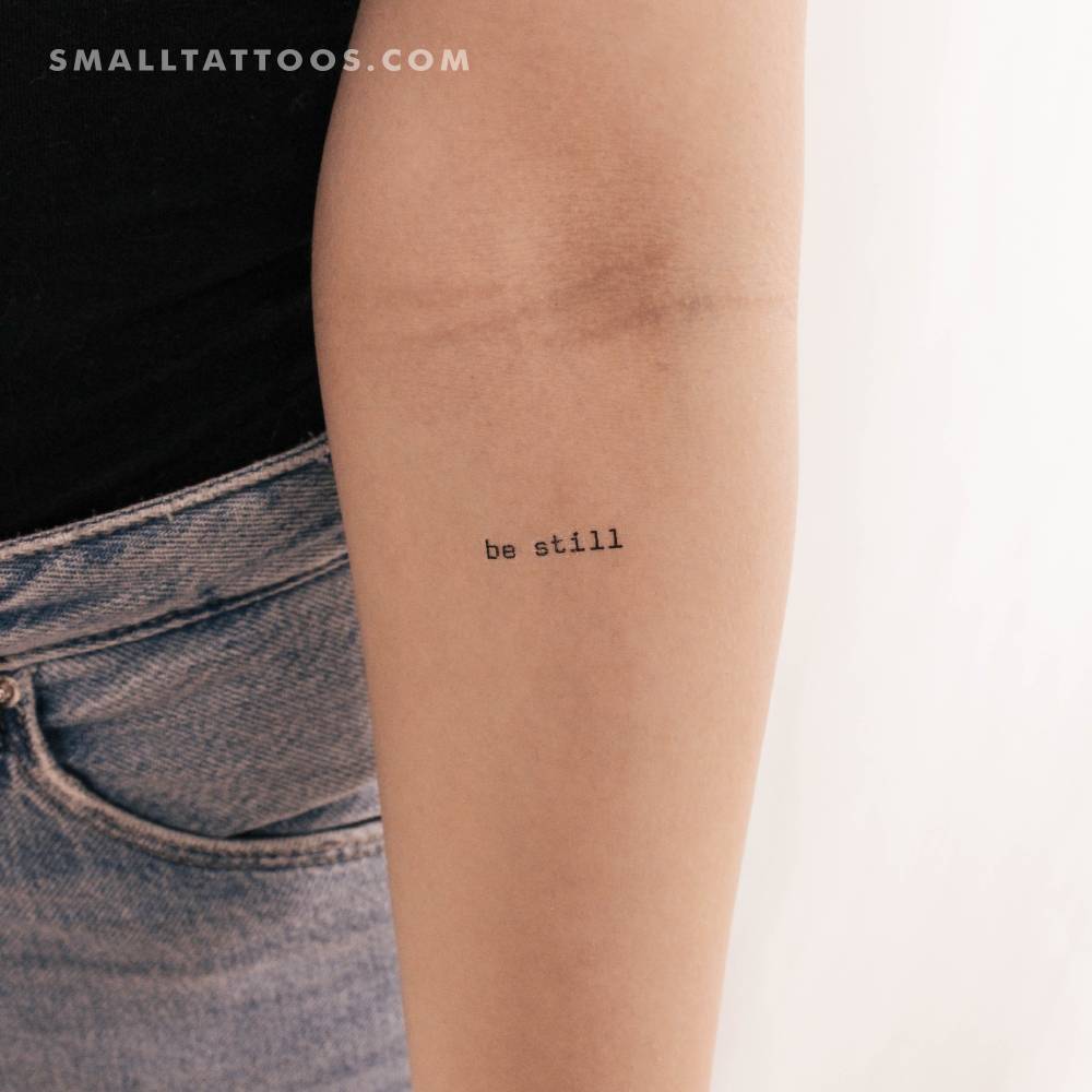 Typewriter font "be still" temporary tattoo located on the inner forearm.