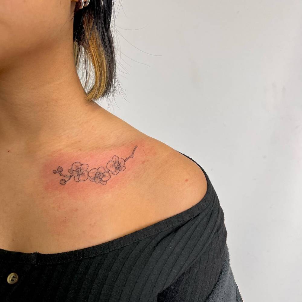 Little orchid tattoo located on the collarbone.