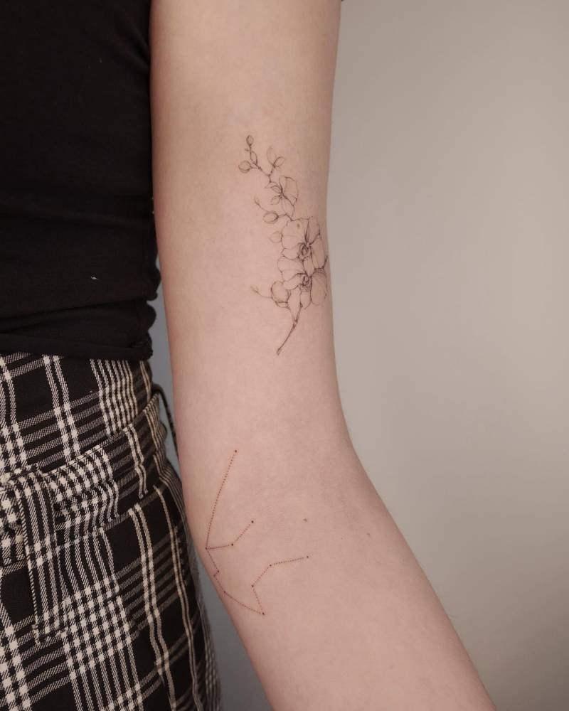 Aquarium constellation and orchid tattoos located on the arm.