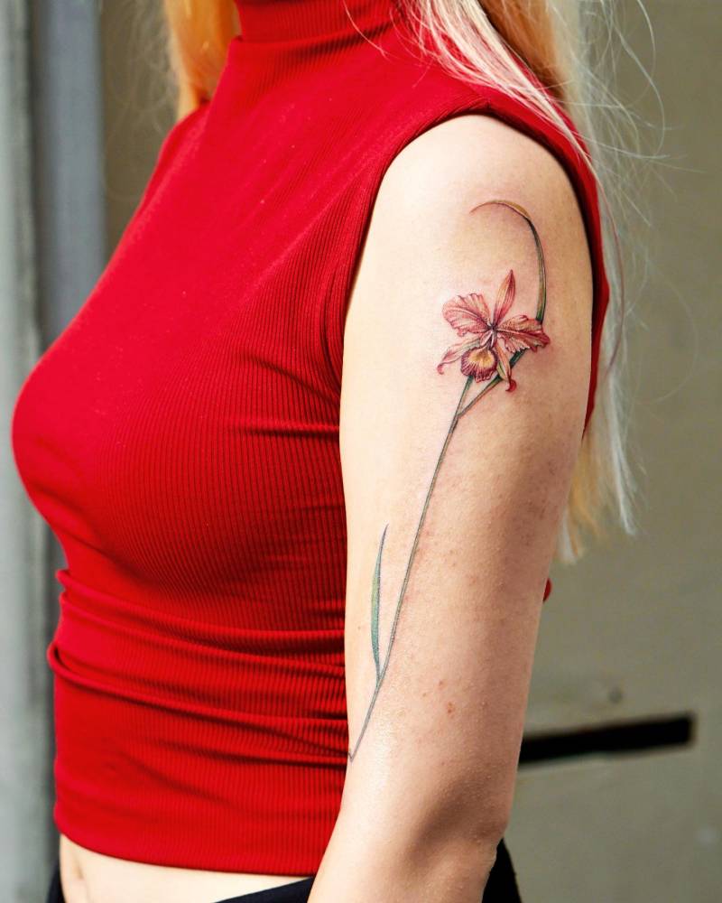 Watercolor style orchid tattoo done on the upper arm.
