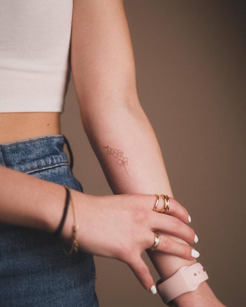 Fine line style orchids tattoo located on the inner forearm.
