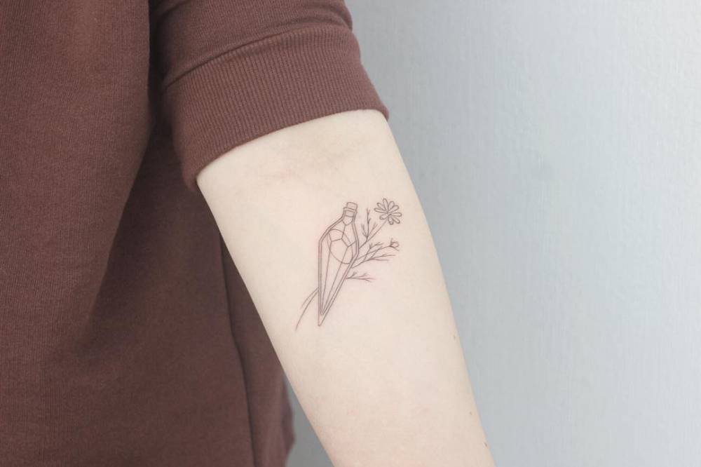 Fine line magical potion tattoo on the inner forearm.