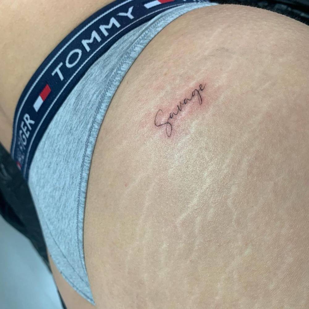 "Savage" lettering tattoo on the hip.