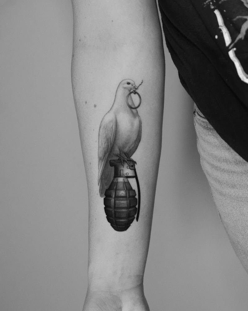 Dove and grenade tattoo in micro-realistic style located on the inner forearm.