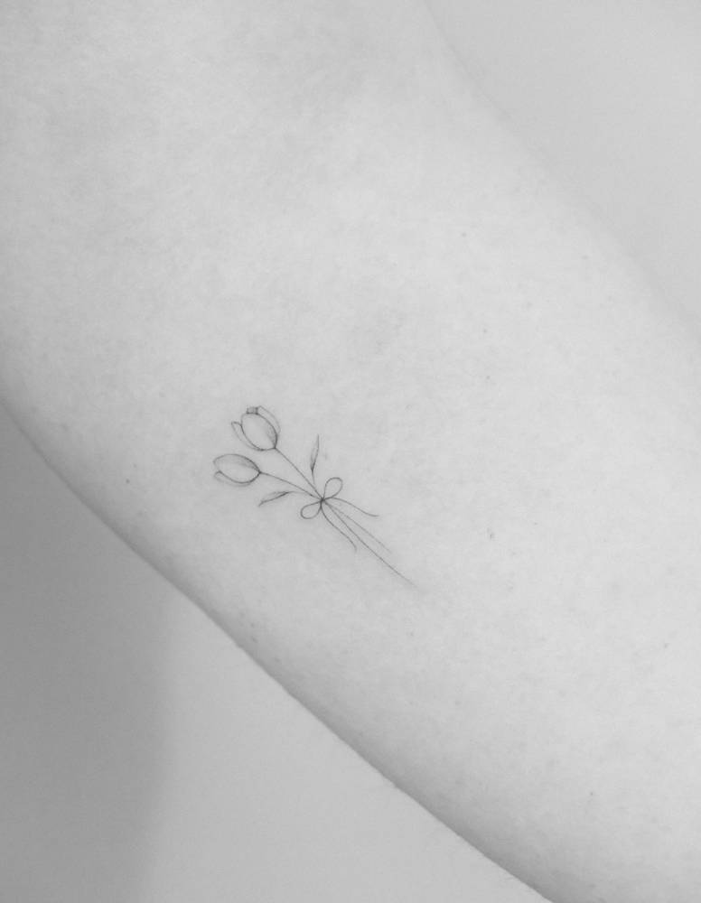 Tulips in fine line style tattooed on the inner forearm.