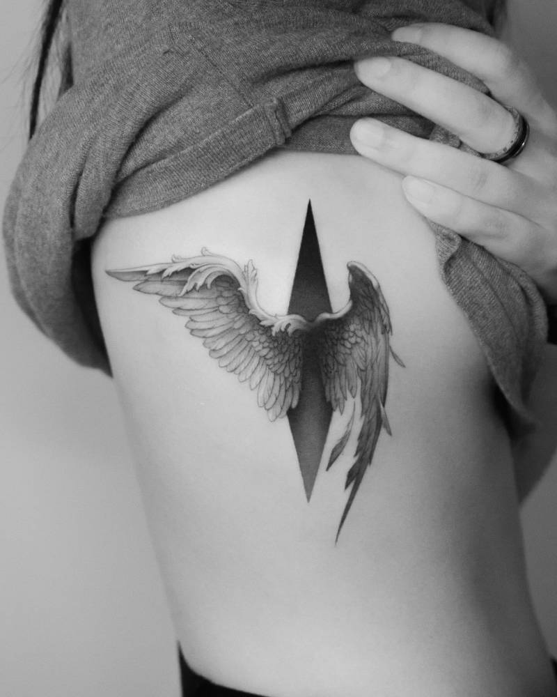 Angel wings tattoo in micro-realistic style located on the side boob.