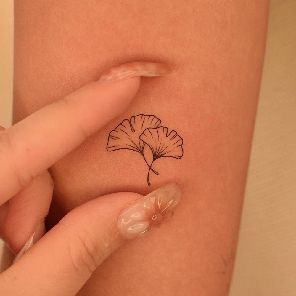 Ginkgo leaves tattoo in fine line style located on the inner arm.