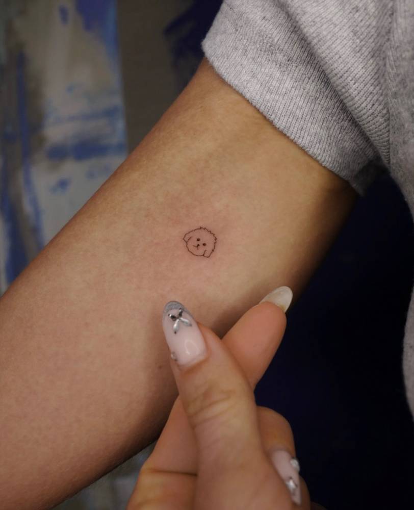 Little dog portrait tattooed on the inner forearm, done in minimalistic style.