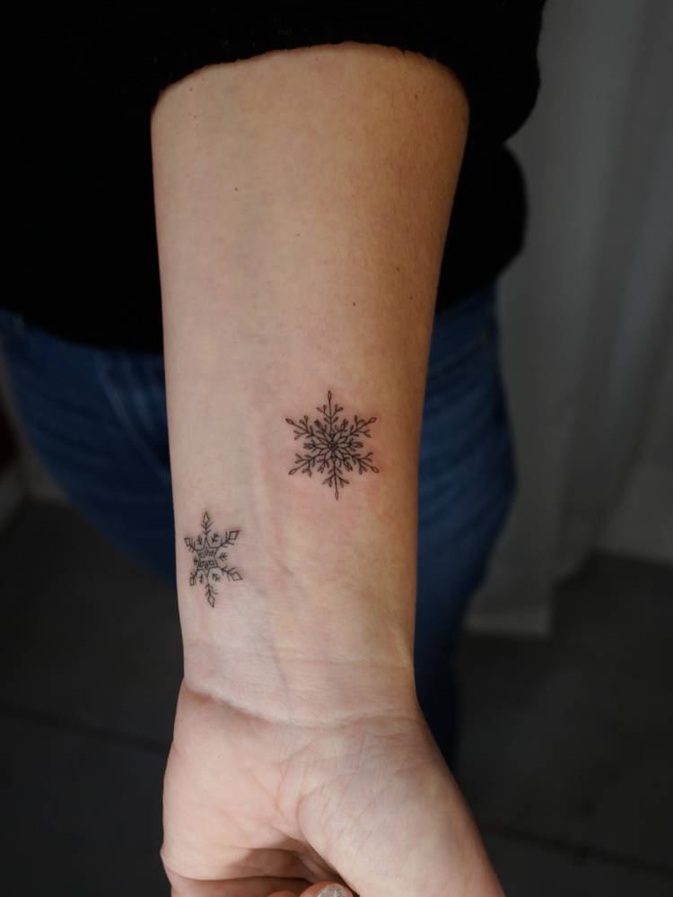 Snowflakes in fine line style tattooed on the wrist.
