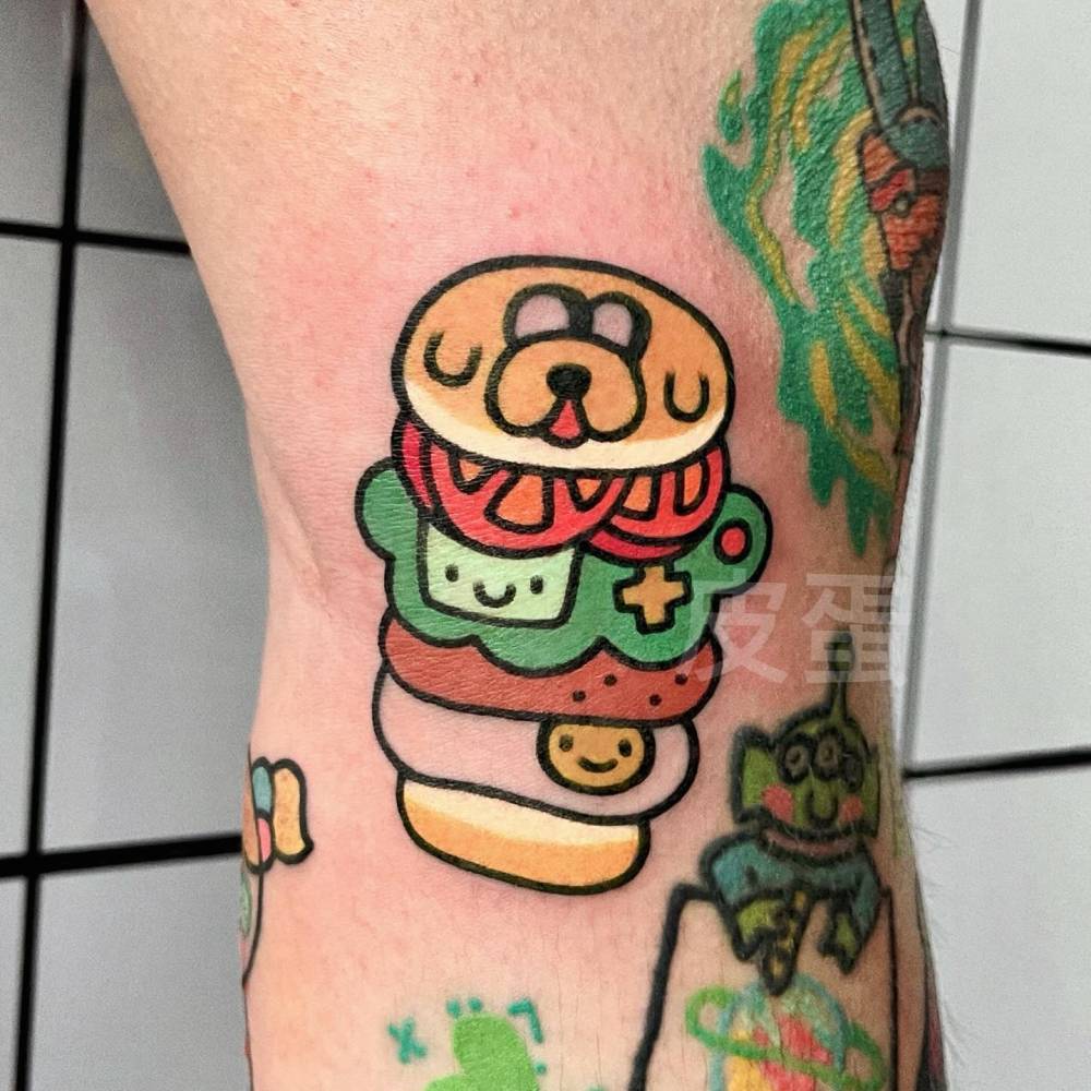Jake The Dog burger tattooed on the knee, cartoon style.