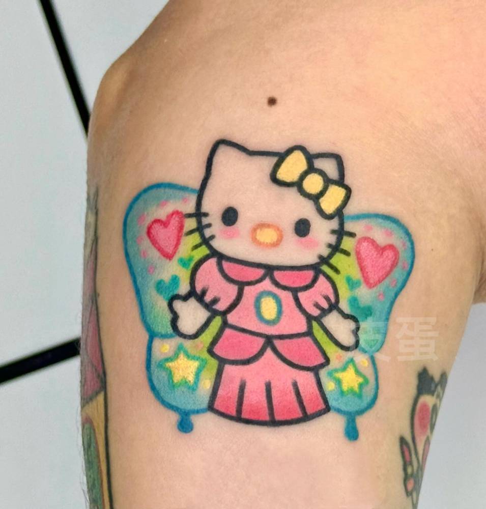 Hello Kitty butterfly tattooed on the forearm, done in cartoon style.