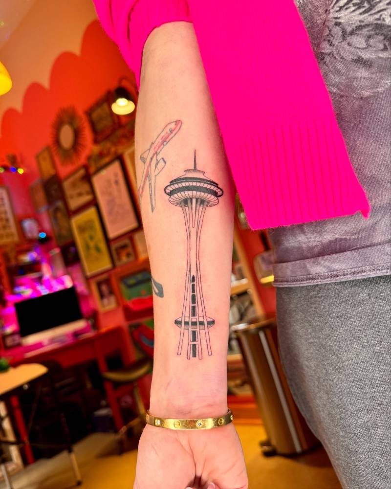 Space needle tattoo in illustrative style located on the inner forearm.