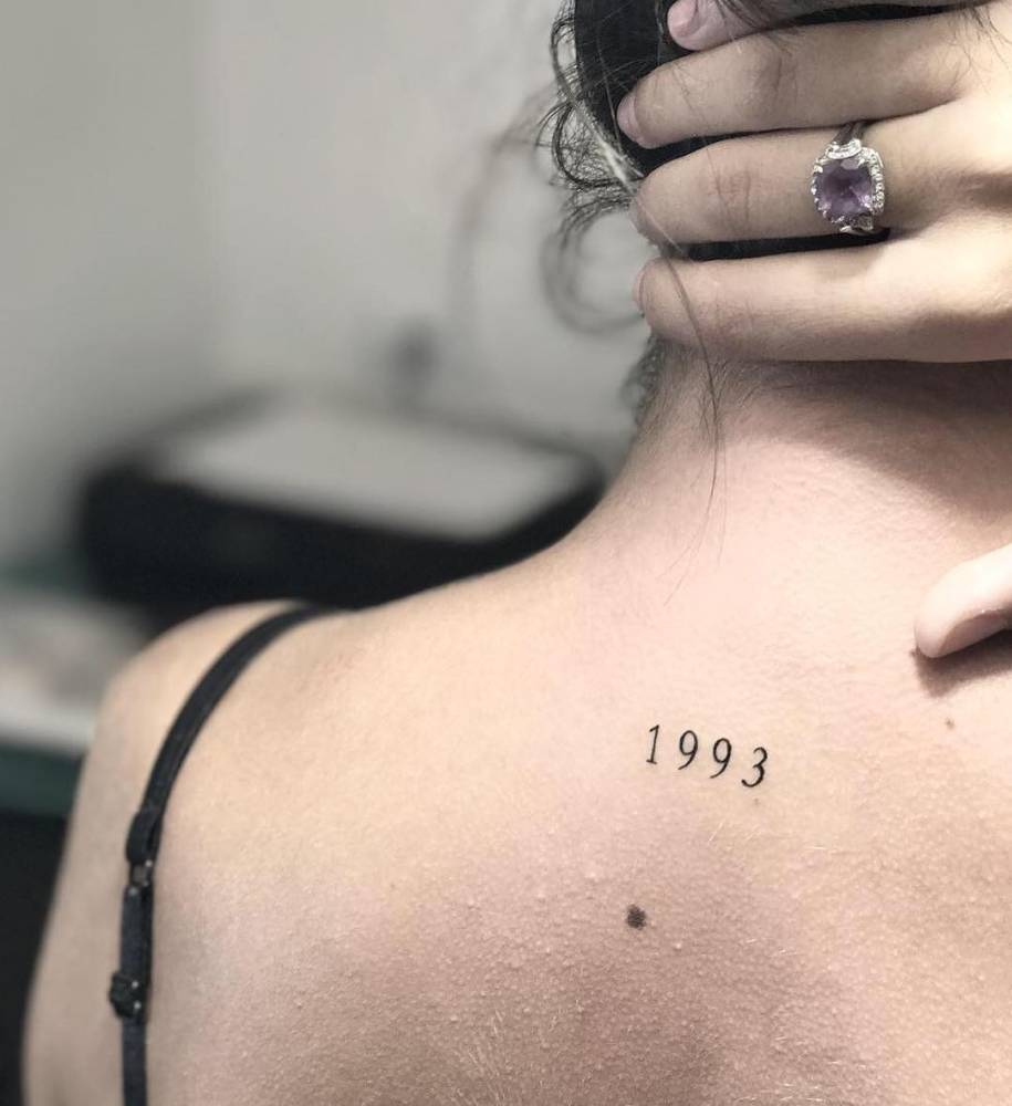 Birth year "1993" tattoo located on the upper back.