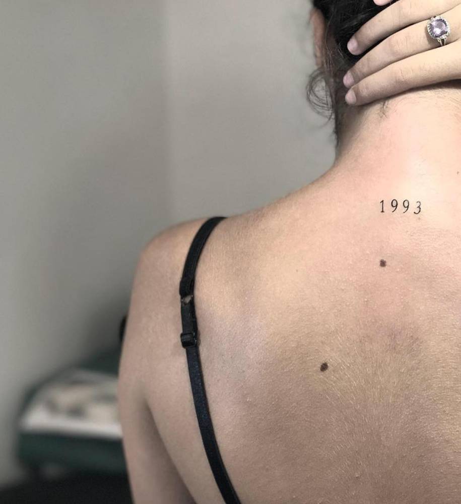 Birth year "1993" tattoo located on the upper back.