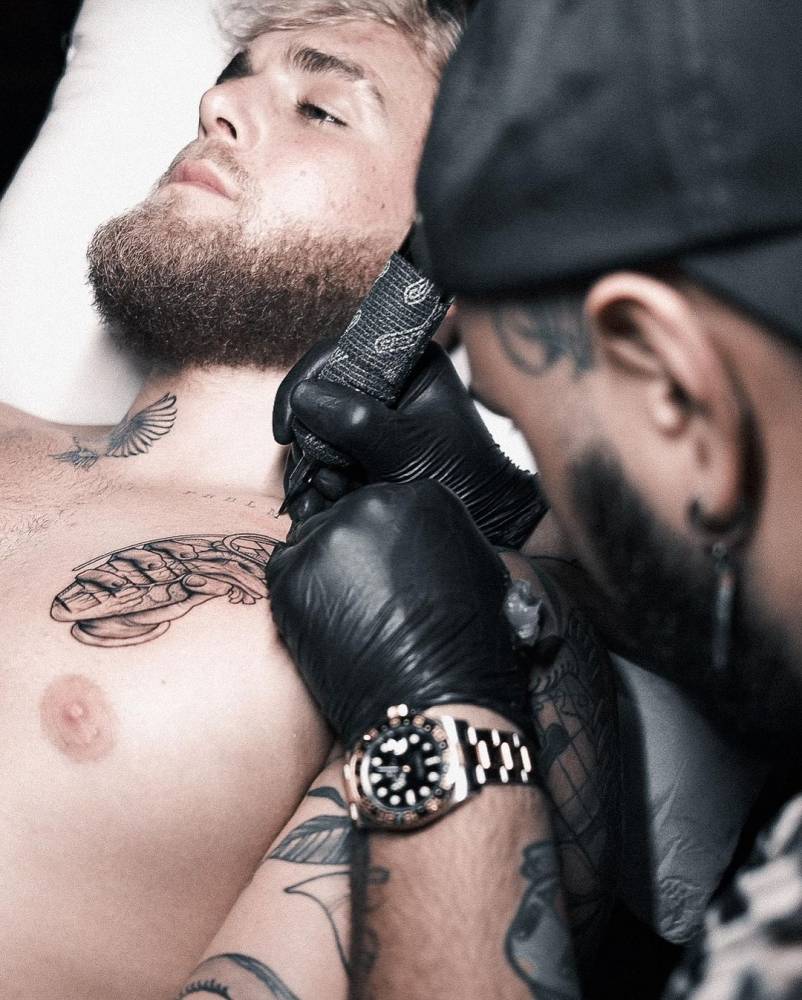 Hand holding a heart shaped grenade tattooed on Jake Paul's chest