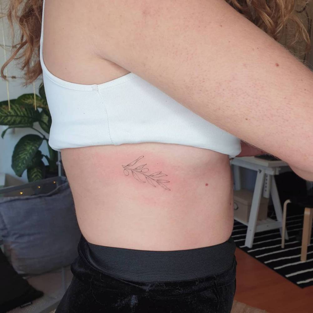 Fine line olive branch tattoo on the rib.