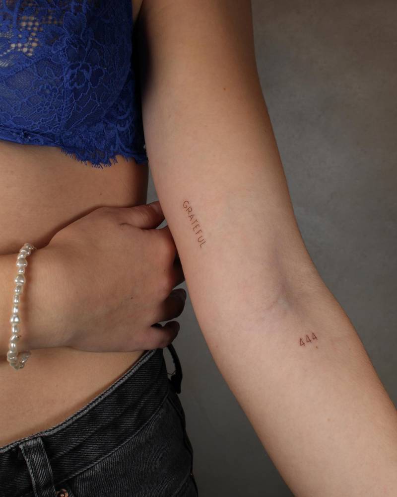 Word "grateful" and number "444" tattooed on the arm.