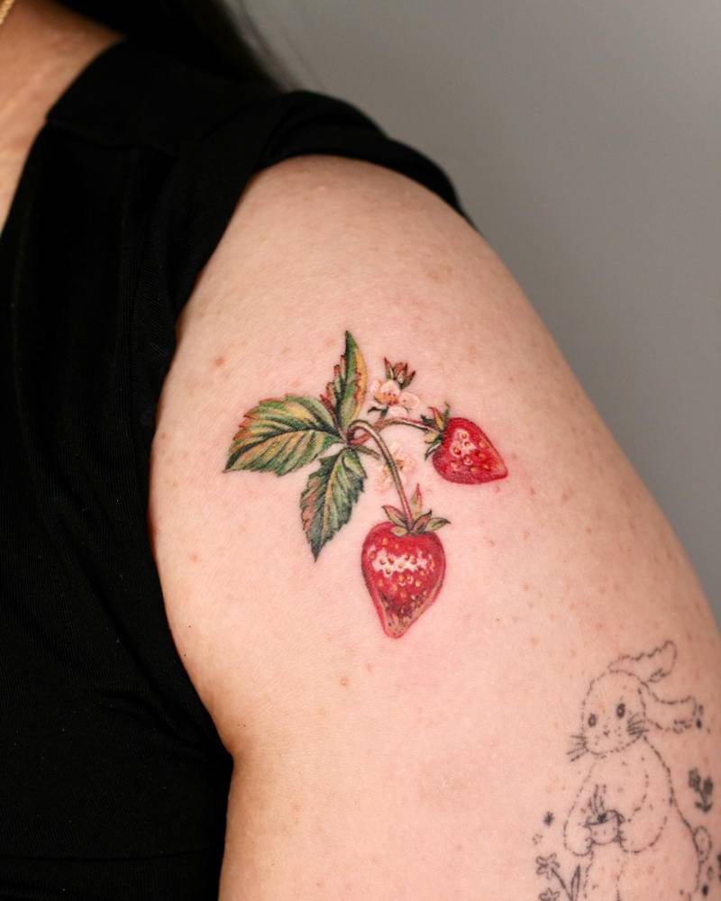 Watercolor style strawberries tattoo placed on the shoulder.