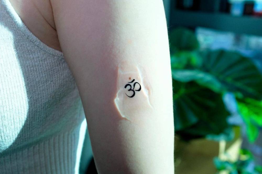 Minimalistic style Om birthmark cover up tattoo.
