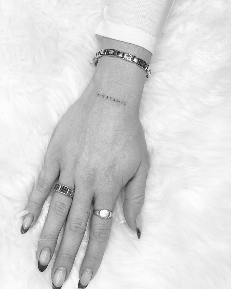 "Timeless" lettering tattoo on the wrist.