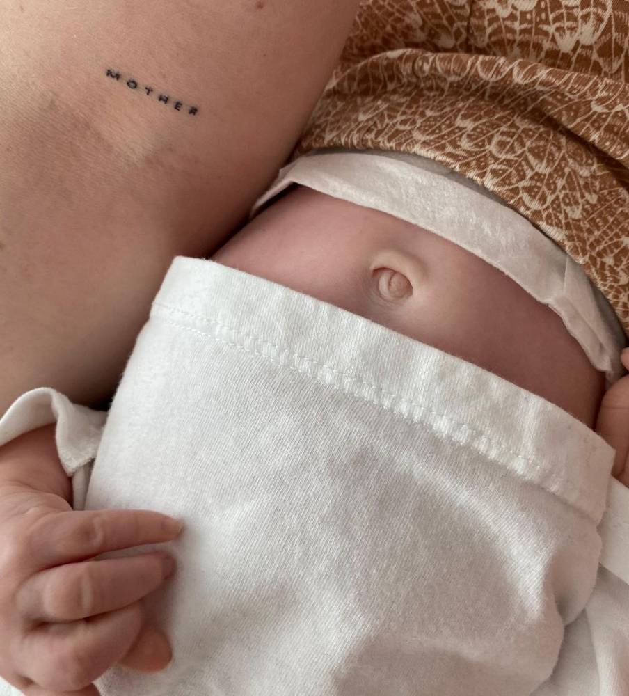 Hand poked "Mother" lettering tattoo on the bicep.