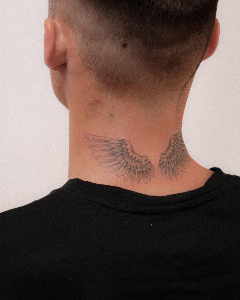 Wings tattoo located on the back of the neck.