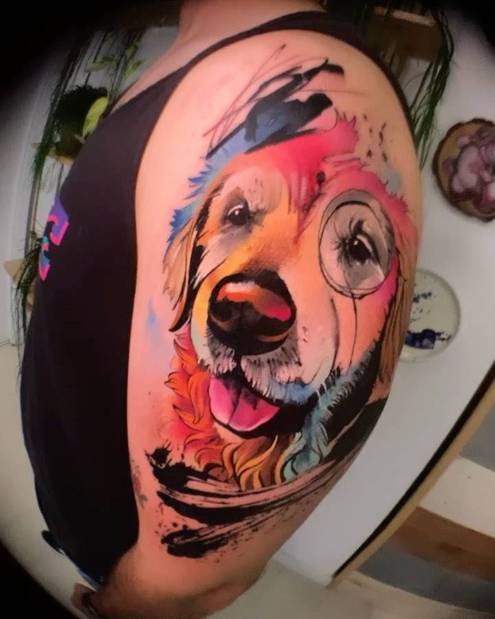 Watercolor style golden retriever portrait tattoo on the upper arm.