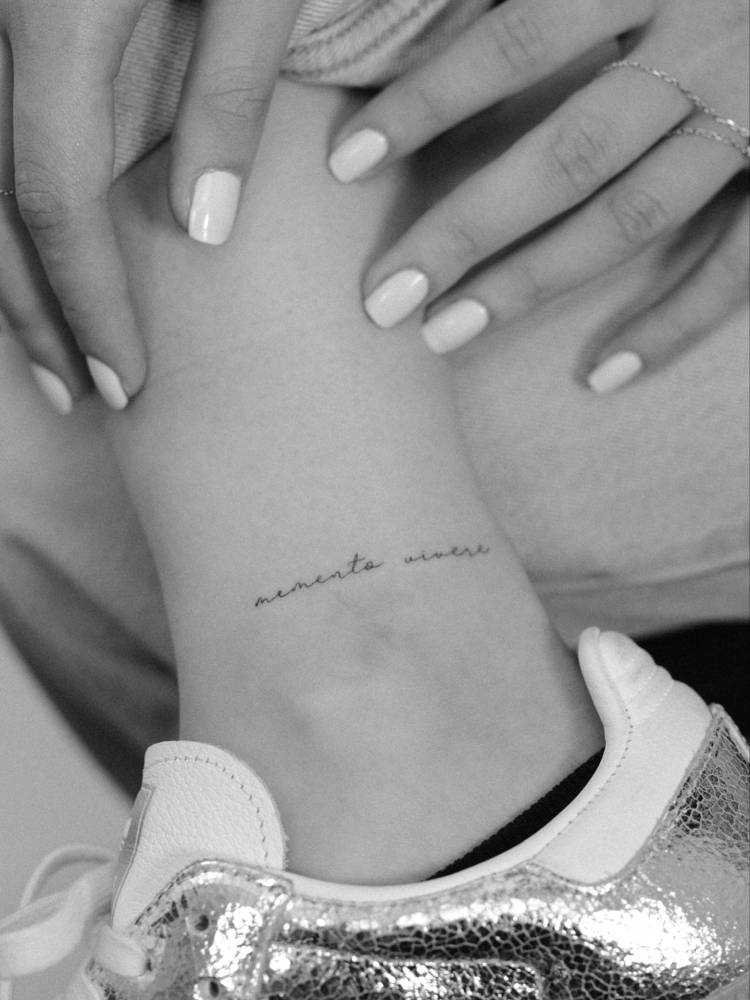 "Memento vivere" lettering tattoo located on the ankle.