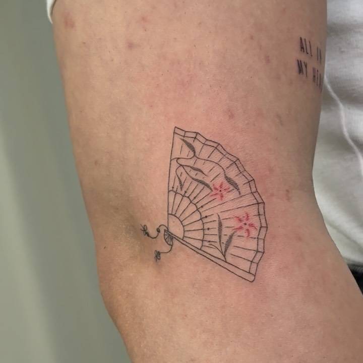 Hand fan tattoo in fine line style located on the elbow.