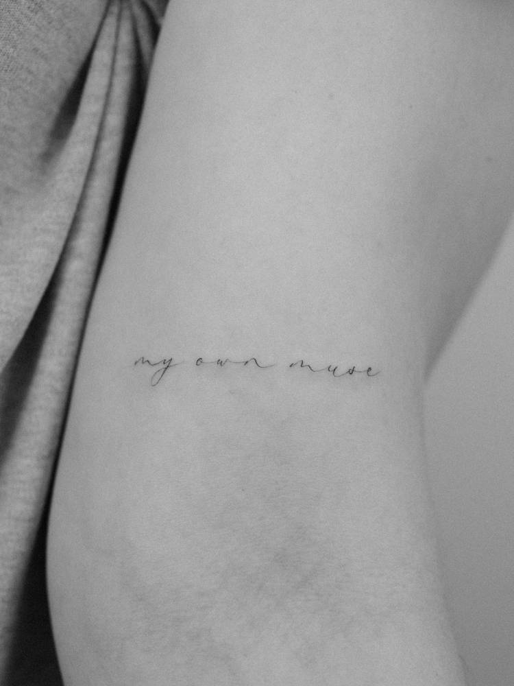 "My own muse" lettering tattoo located on the bicep.