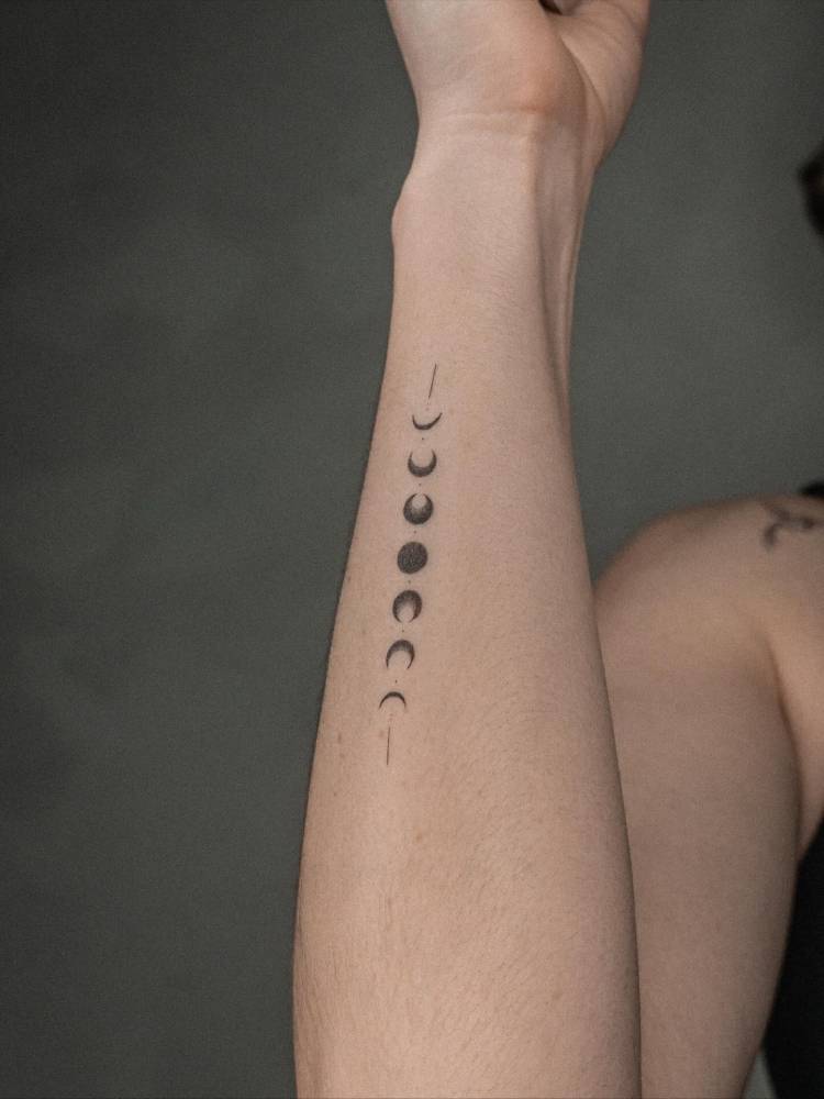 Moon phases tattoo located on the wrist, minimalistic style.