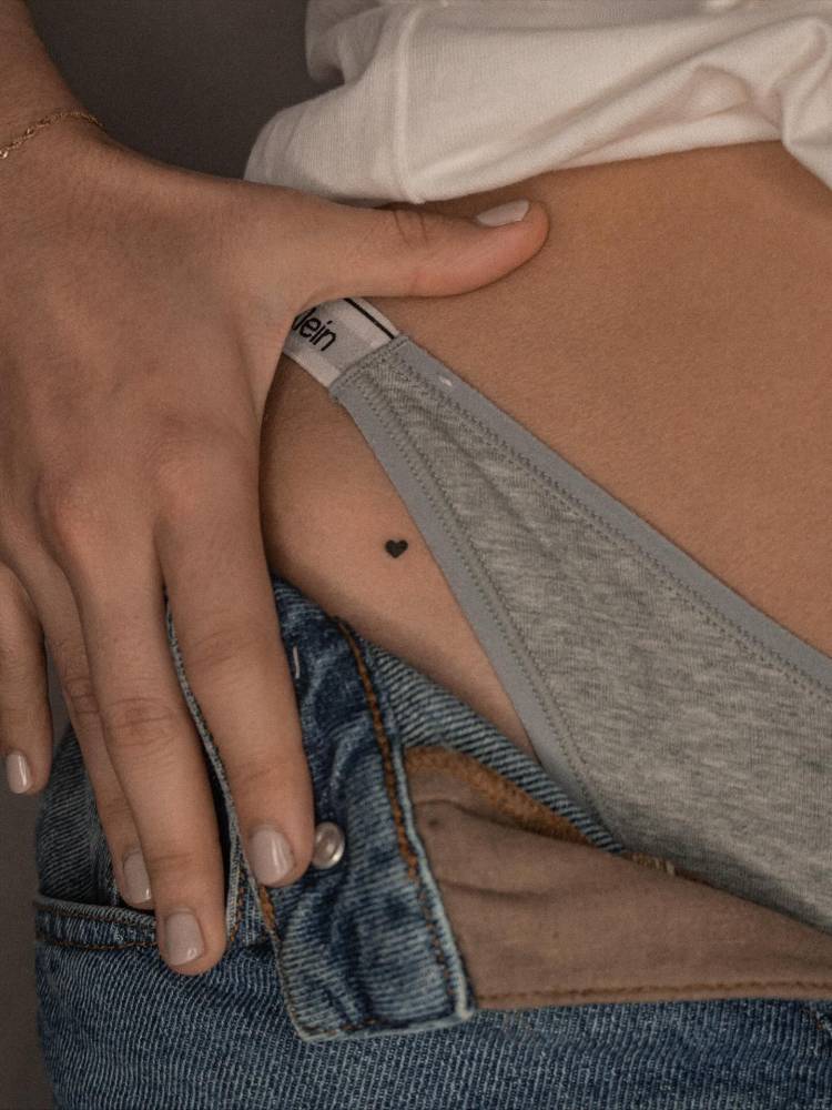 Tiny minimalistic heart tattoo placed on the pelvis.