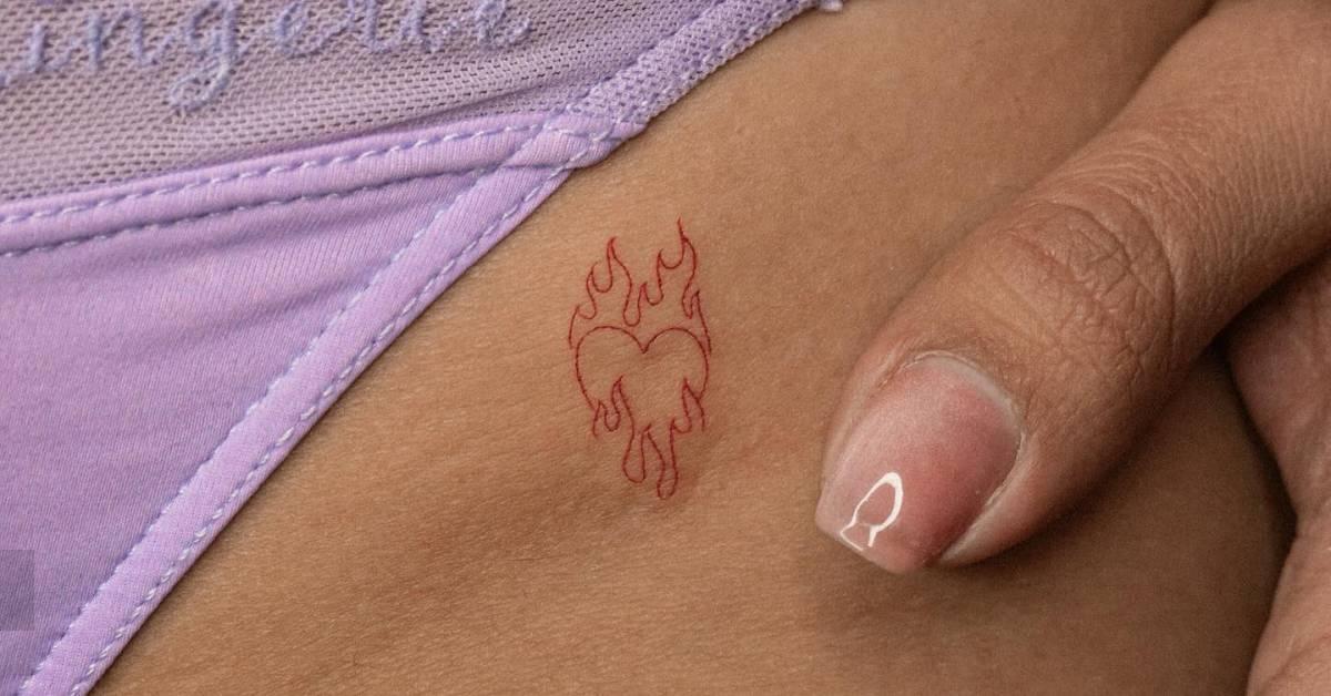 Red flaming heart tattoo located on the pelvis.