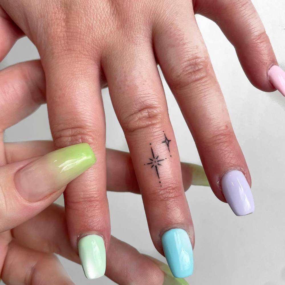 Sparkling stars tattoo located on the finger, minimalistic style.