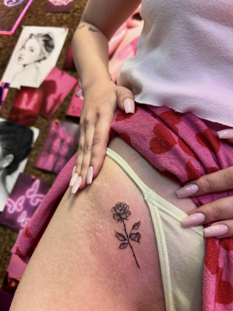 Rose tattoo in illustrative style located on the pelvis.