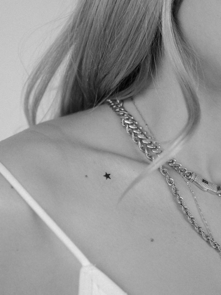 Little star in minimalistic style tattooed on the collarbone.