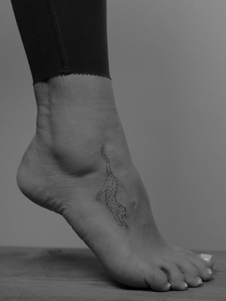 Leopard tattoo in fine line style located on the foot.