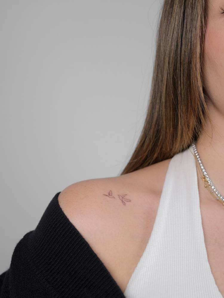 Tiny one line hummingbirds tattooed on the shoulder.