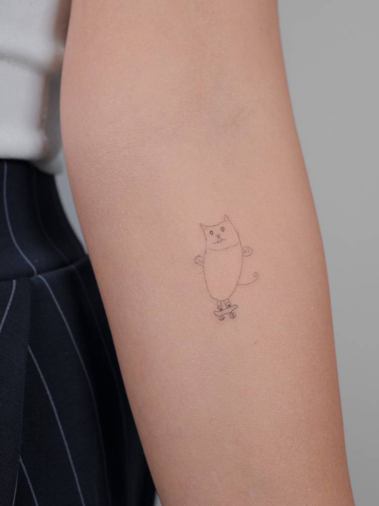 Child's drawing skater cat tattoo located on the inner forearm.