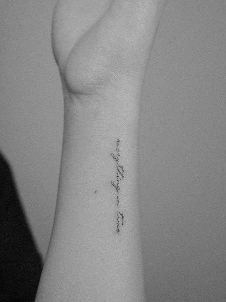Lettering tattoo that says "everything in time" located on the wrist.