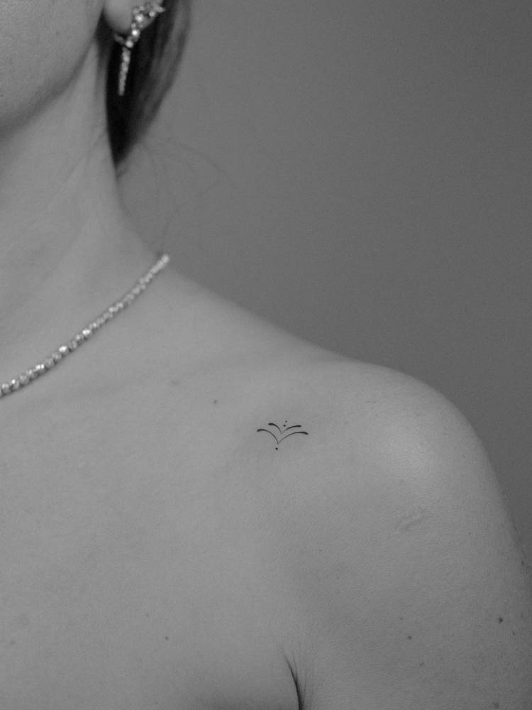 Minimalistic style ornamental tattoo located on the shoulder.
