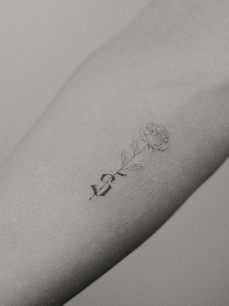 Fine line style and gothic font letter "S" tattooed on the inner forearm.