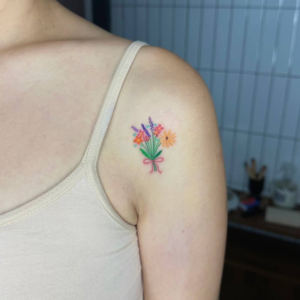 Flower bouquet tattoo in watercolor style located on the shoulder.