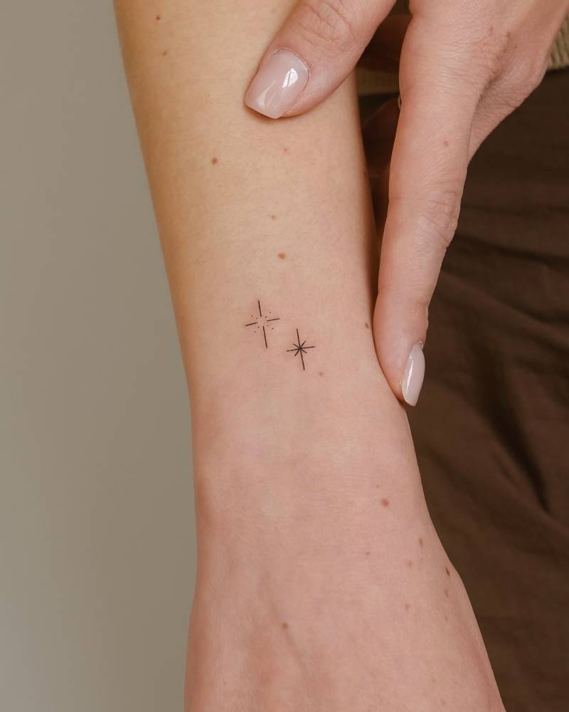 Minimalistic sparkling stars tattoo located on the wrist.
