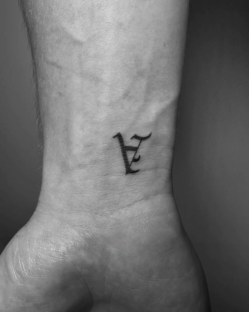 Gothic font letter "A" tattoo located on the wrist.