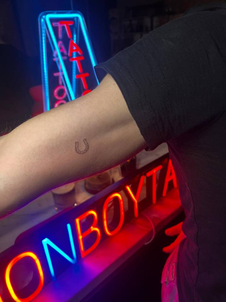 Minimalistic horseshoe tattoo located on the inner arm.