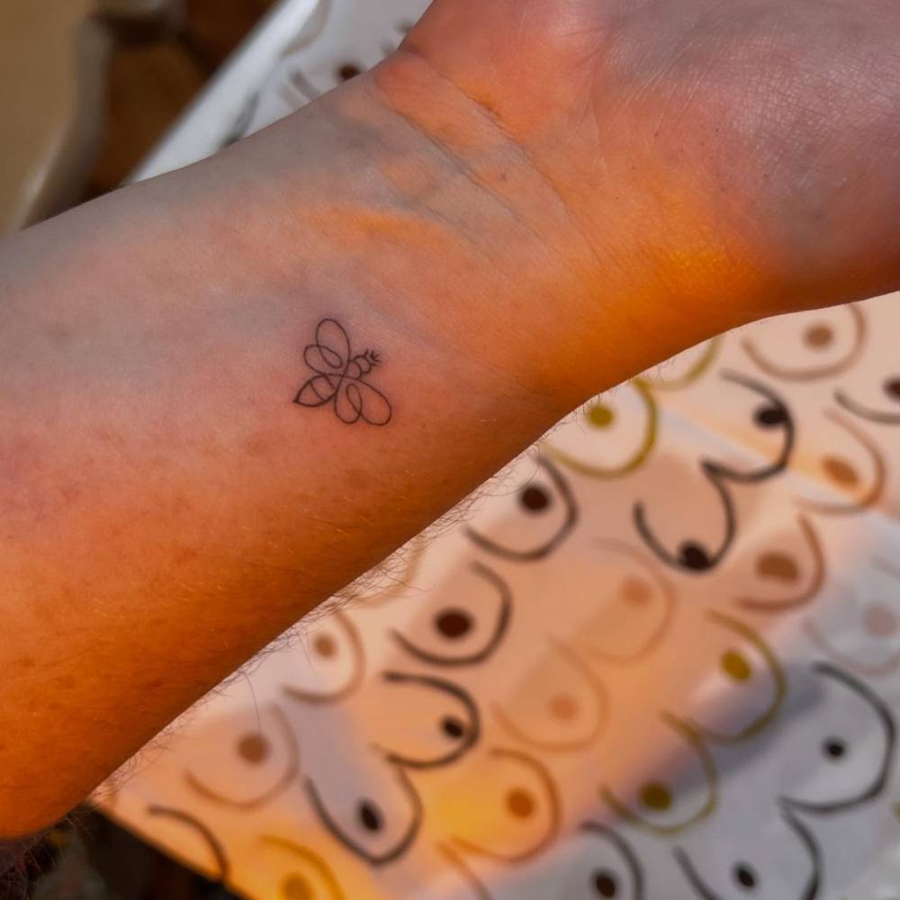 Little bee tattoo located on the wrist, done in minimalistic style.