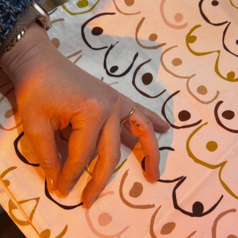 Tiny lettering tattoo of the number "24" located on the finger.