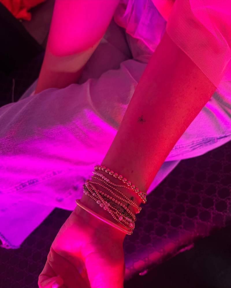 Tiny minimalistic flower tattooed on the wrist.