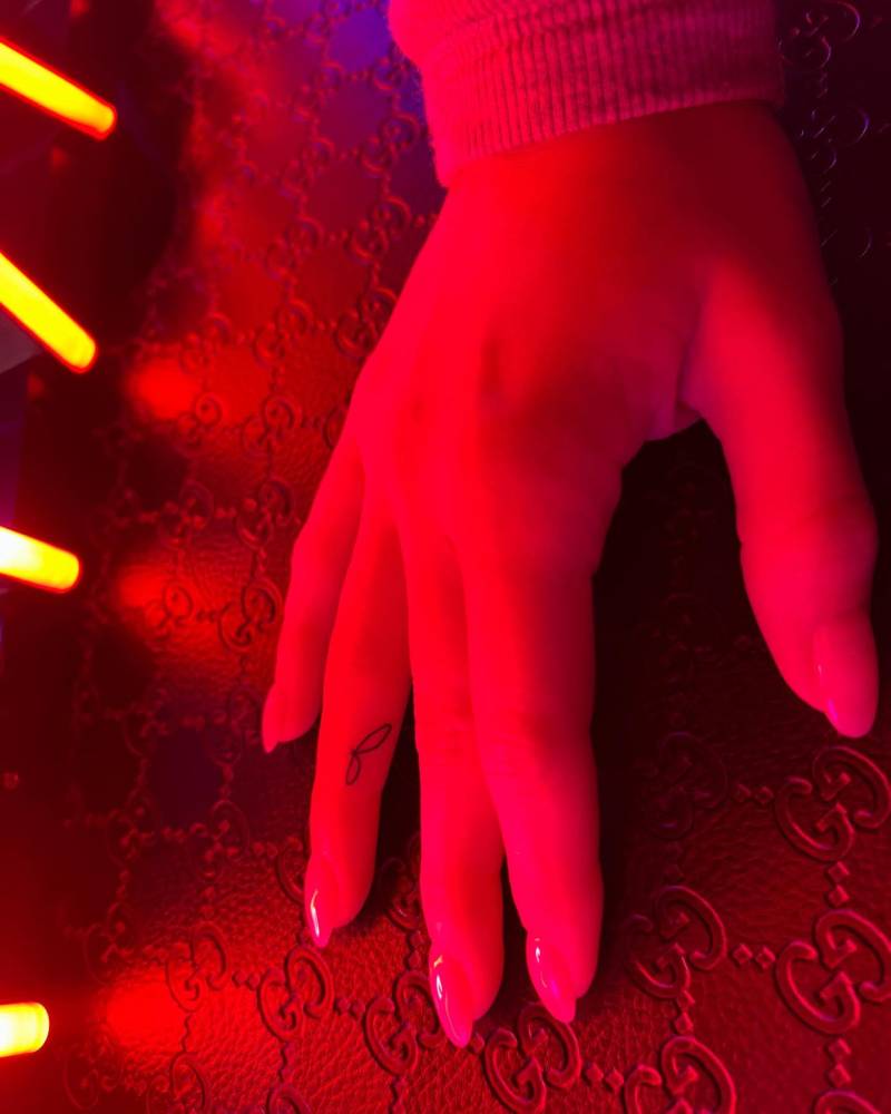 Letter "J" tattoo in handwritten font located on the finger.